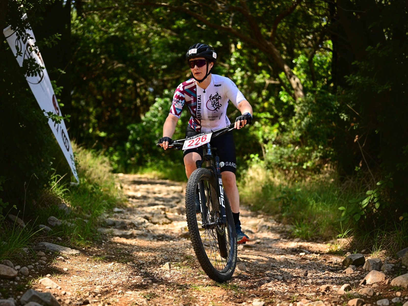 Atleta in mountain bike lungo un sentiero nel bosco.