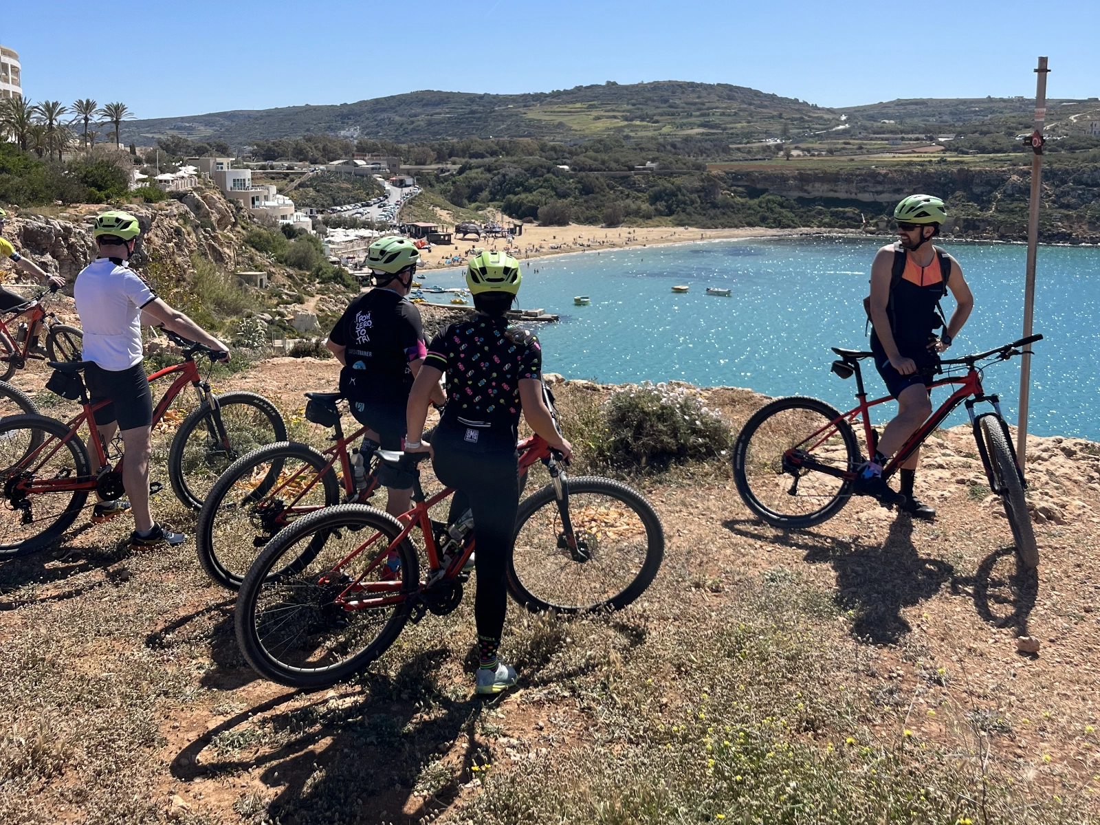 Il gruppo in mountain bike si ferma su un sentiero panoramico sopra la baia.