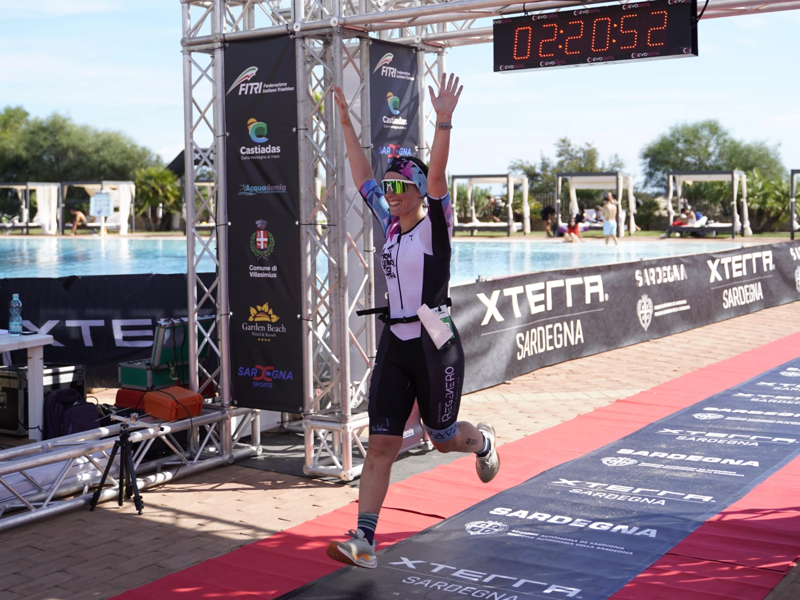 Atleta taglia il traguardo XTERRA con le braccia alzate.