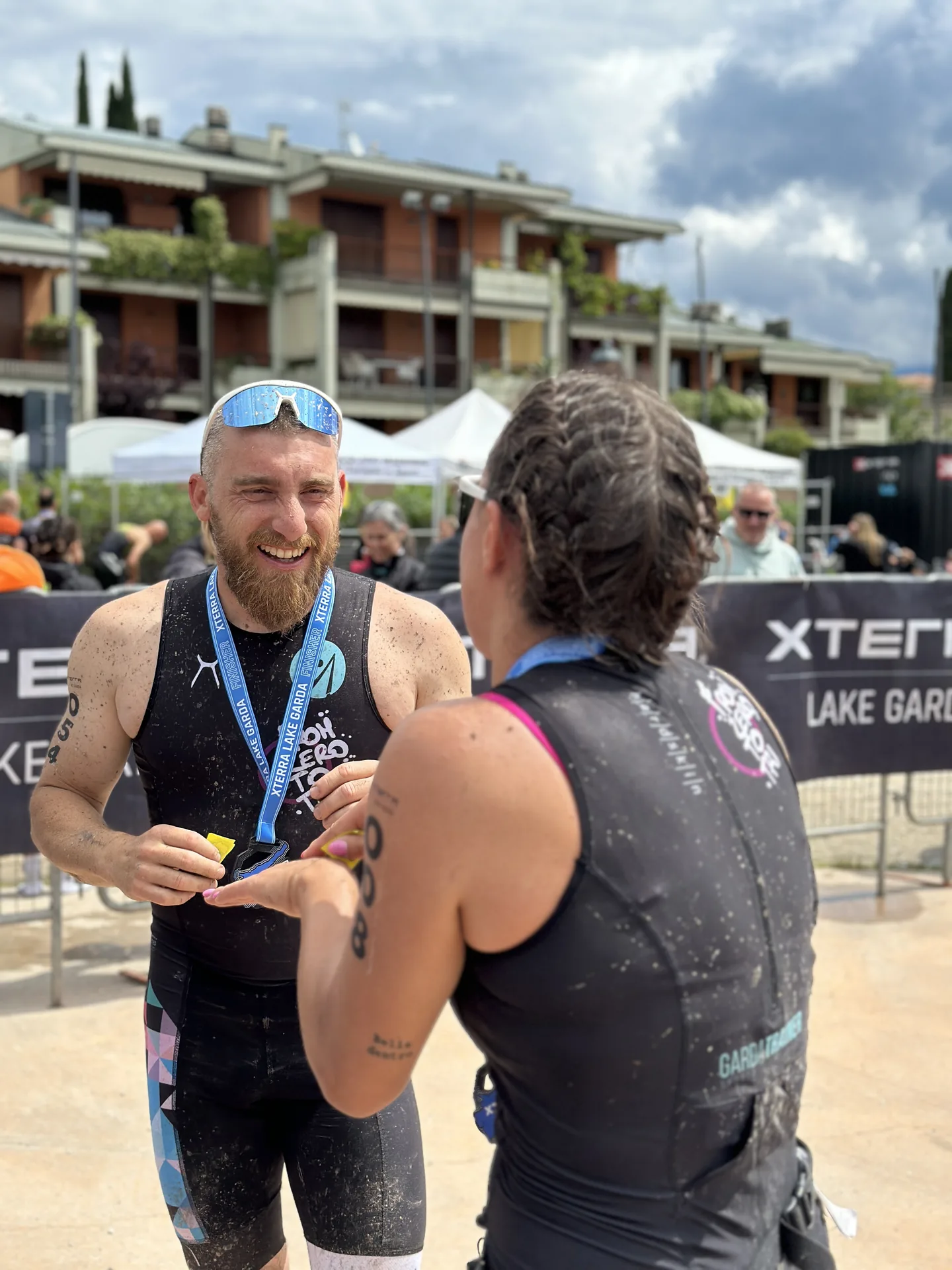 Due atleti in divisa From Zero to Tri con medaglie finisher si sorridono dopo la gara XTERRA Lake Garda.