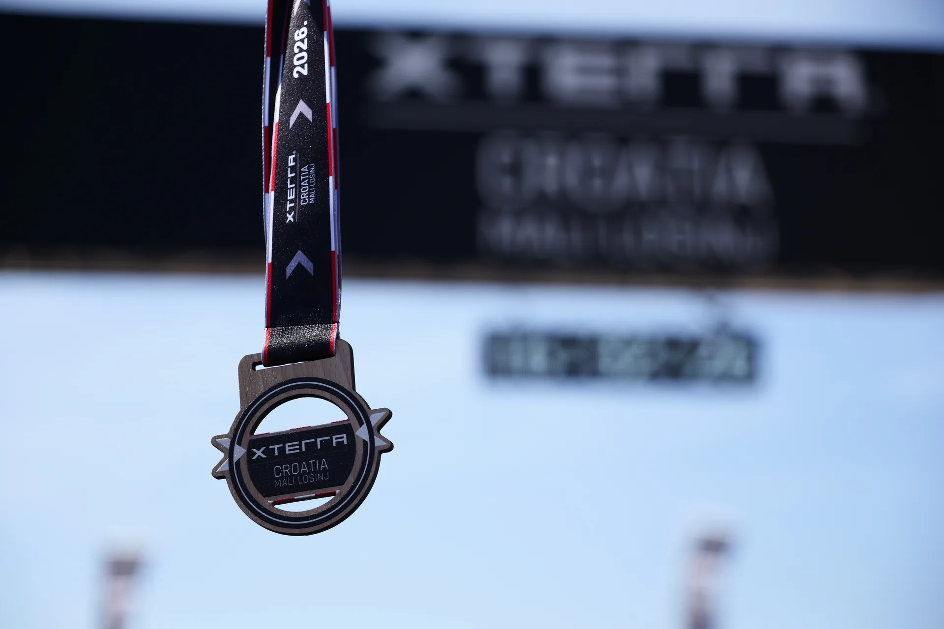Primo piano di una medaglia finisher XTERRA tenuta per il nastro.