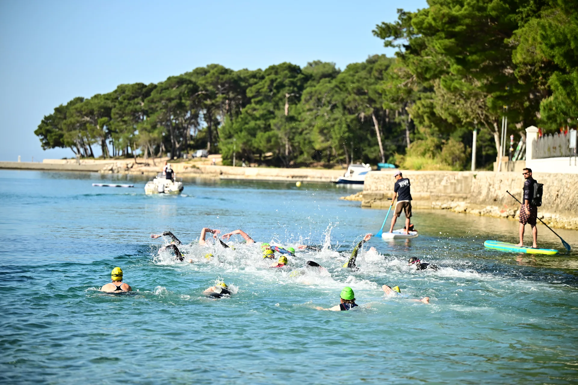 Nuotatori con cuffie colorate in acqua vicino alla riva della baia.