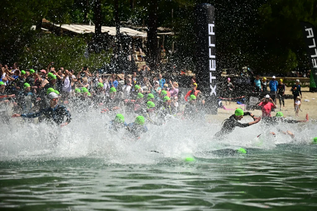 Atleti che si tuffano e corrono in acqua alla partenza della frazione di nuoto XTERRA.