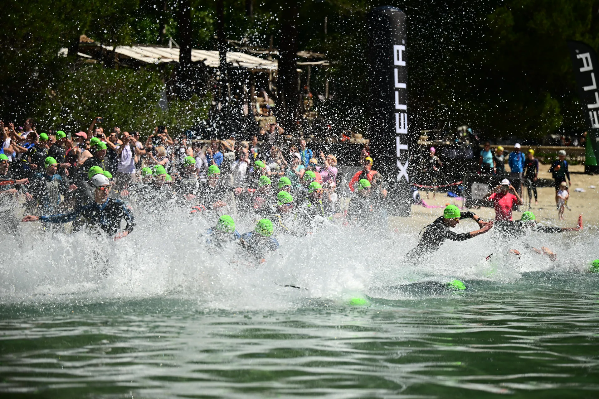 Atleti che si tuffano e corrono in acqua alla partenza della frazione di nuoto XTERRA.