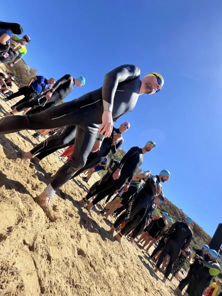 Atleti in muta riuniti sulla spiaggia prima di entrare in acqua.
